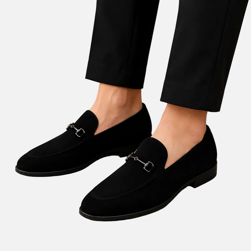 Black loafers worn with black pants on a beige background