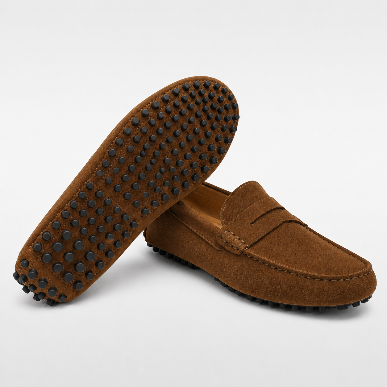 Brown suede loafer with black tread sole on a light gray background