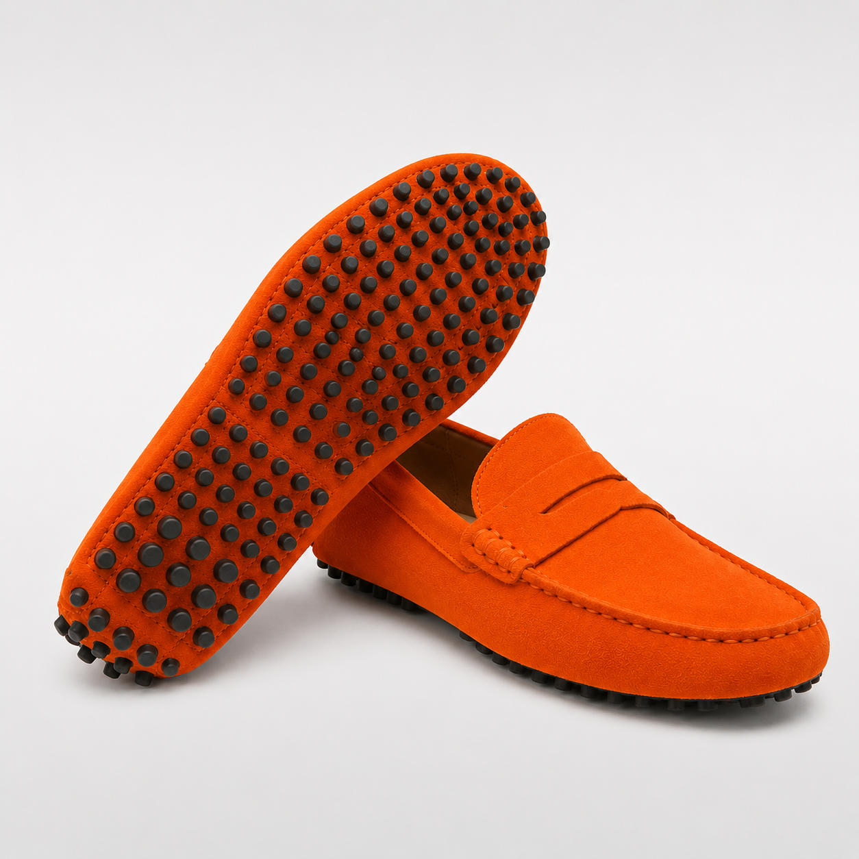 Orange loafers with black tread pattern on a light gray background