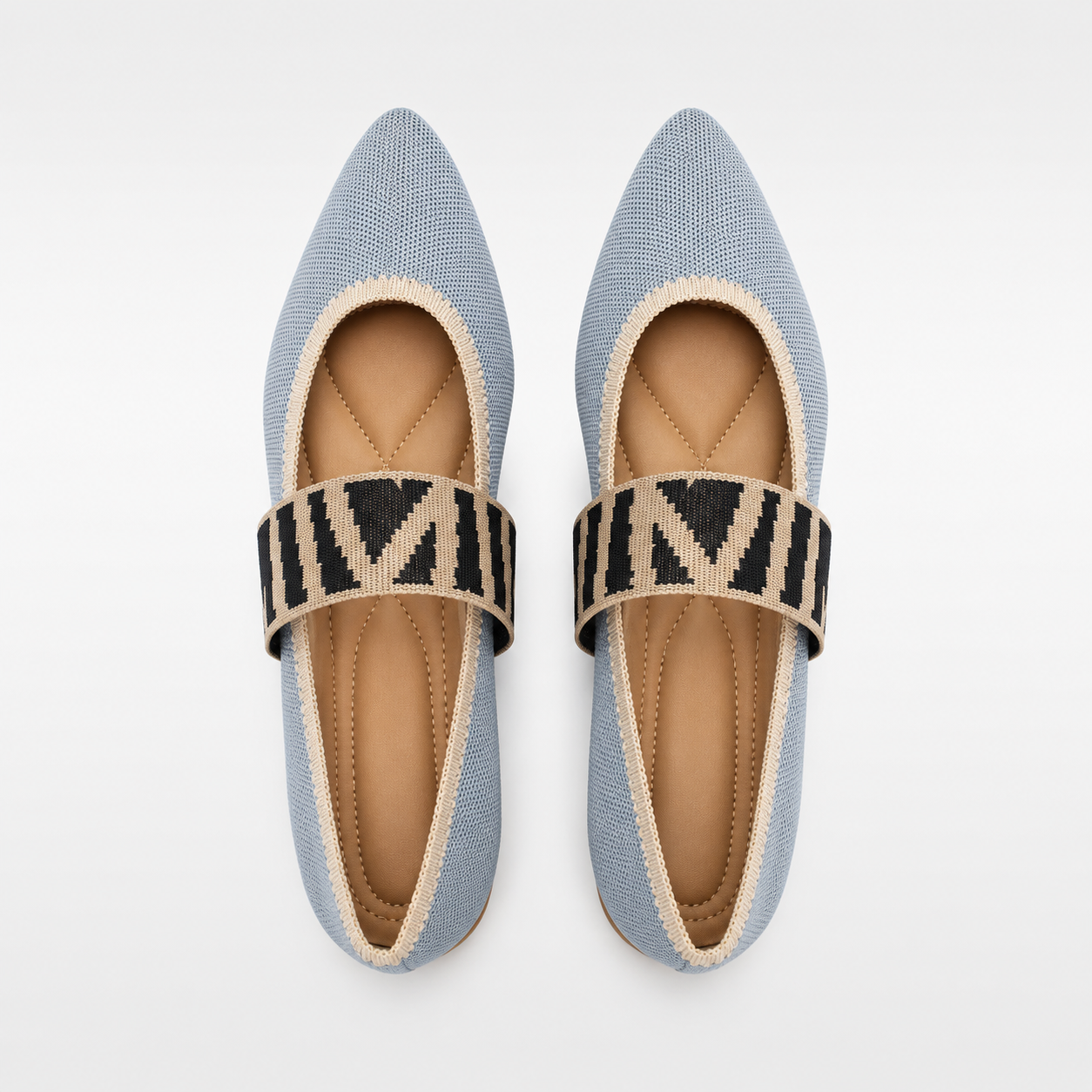 Pair of light blue pointed-toe flats with a patterned strap on a white background