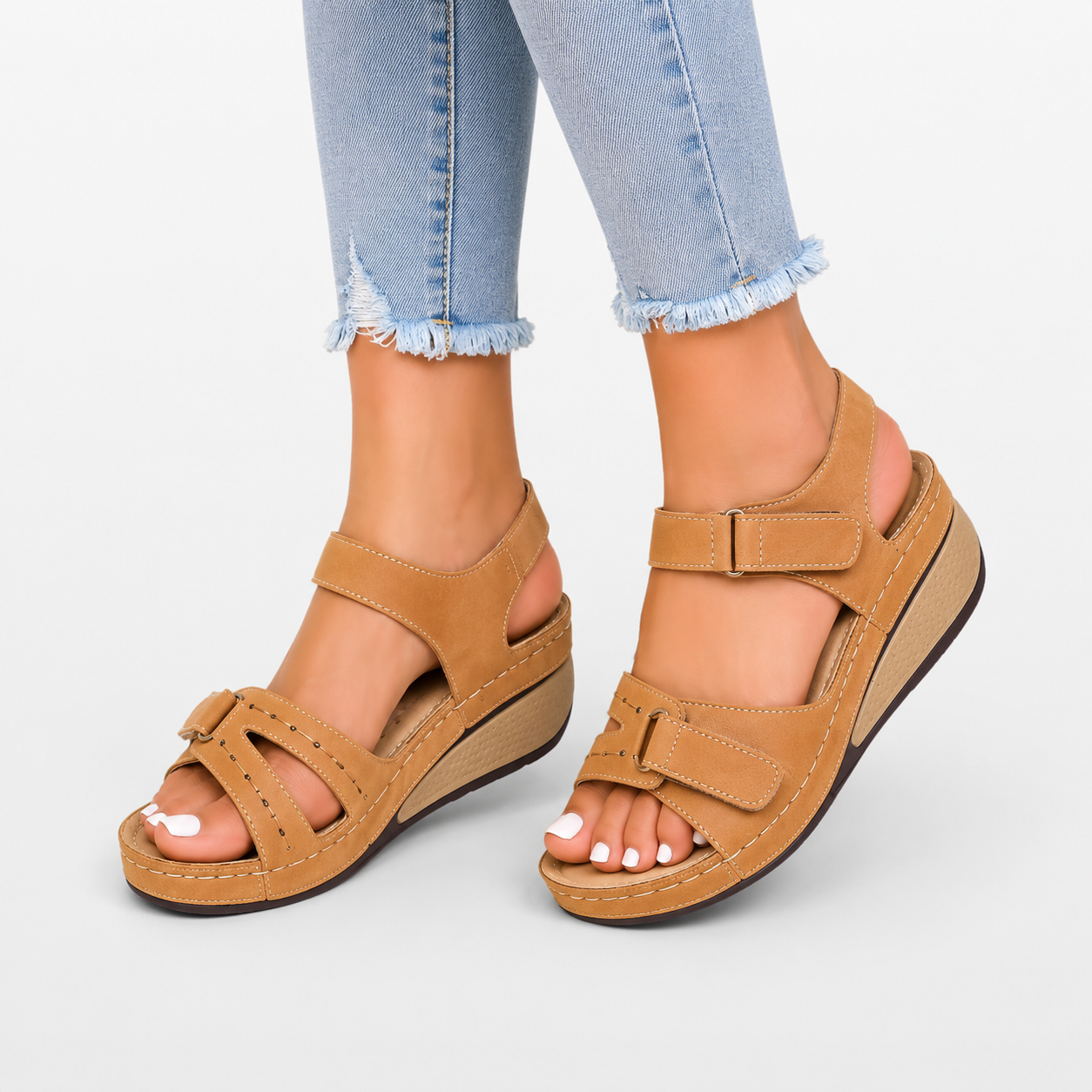 Tan sandals worn with light blue jeans on a white background