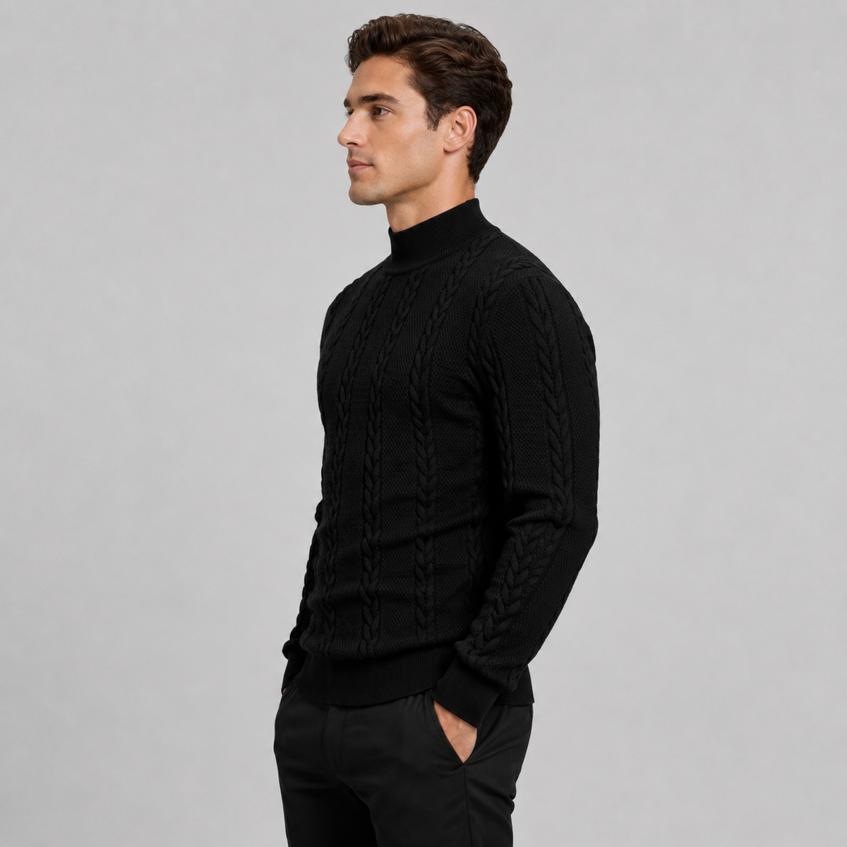 A man wearing a black cable-knit mock neck sweater, shown in profile against a solid light gray studio background.