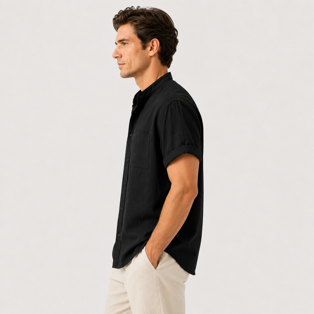 Man wearing a black short-sleeve shirt and light-colored pants against a plain background