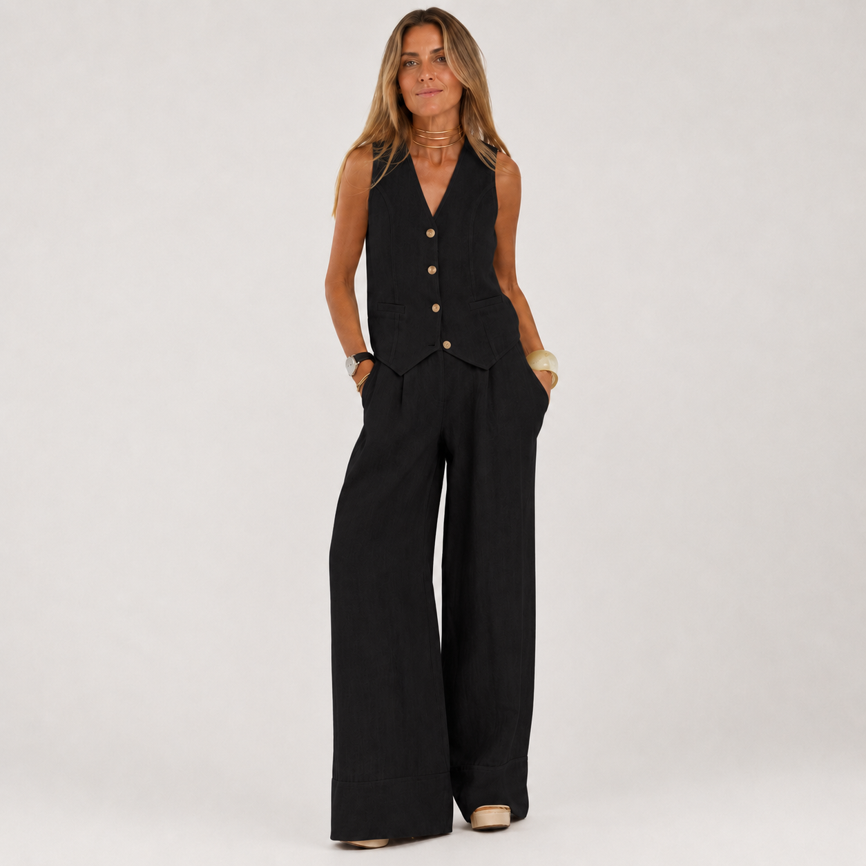 Woman wearing a black sleeveless top and wide-leg pants on a white background