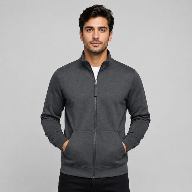 A man wearing a dark gray zip-up hoodie with a stand collar and front pockets, standing against a light gray studio background.