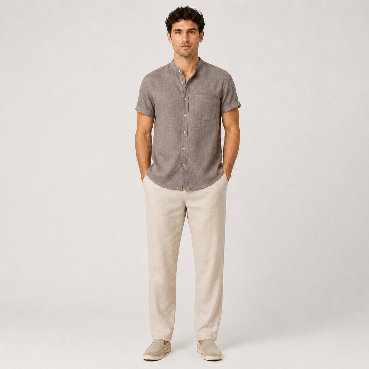 Man wearing a gray button-up shirt and beige pants on a white background