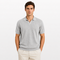 Man wearing a gray polo shirt and beige pants on a white background