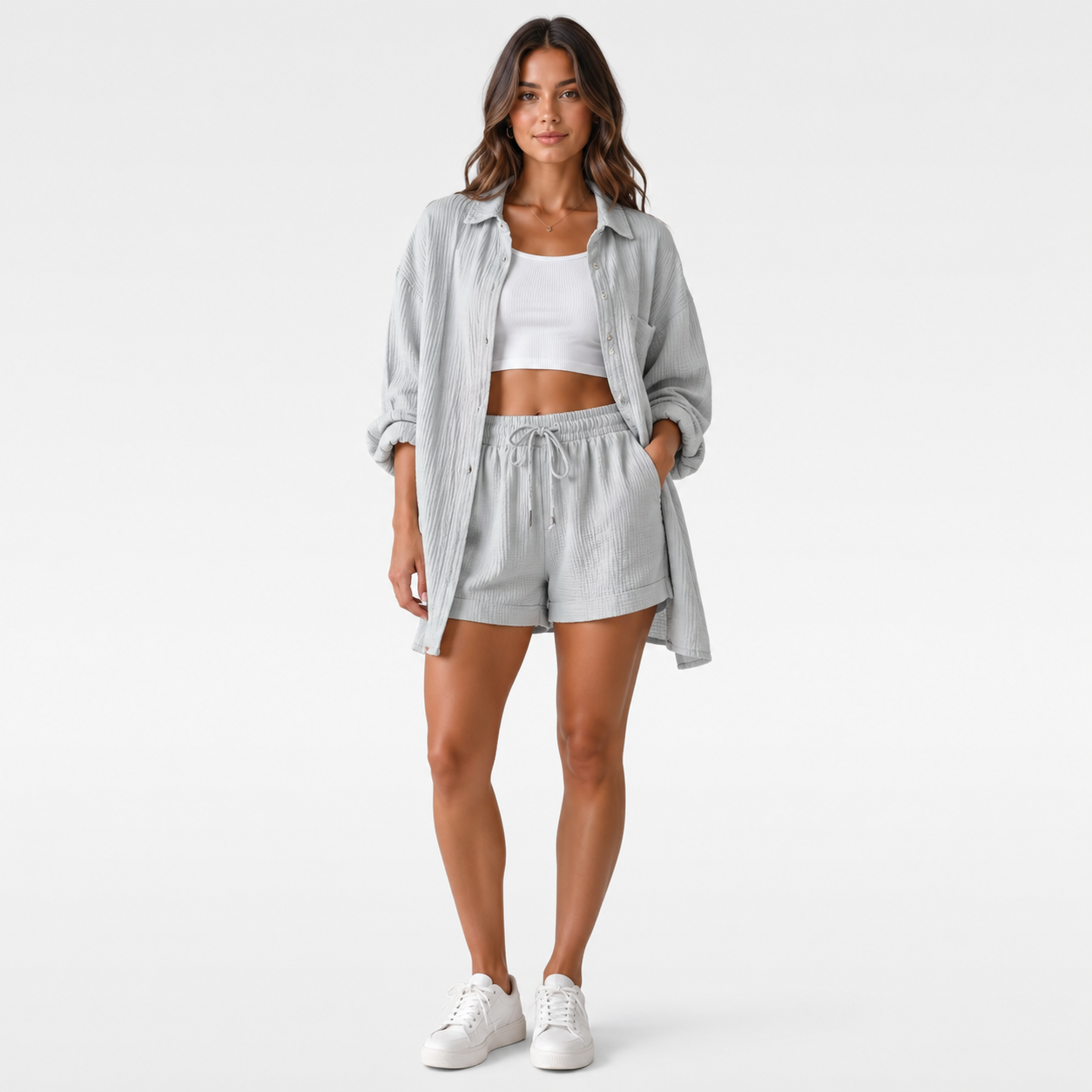 Woman wearing a gray shirt and shorts with a white top underneath on a white background