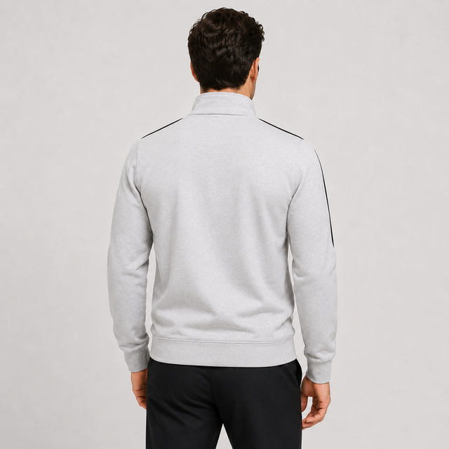 A man viewed from behind wearing a light gray heather quarter-zip sweatshirt with black shoulder and sleeve stripe details, paired with black pants, against a light gray studio background.