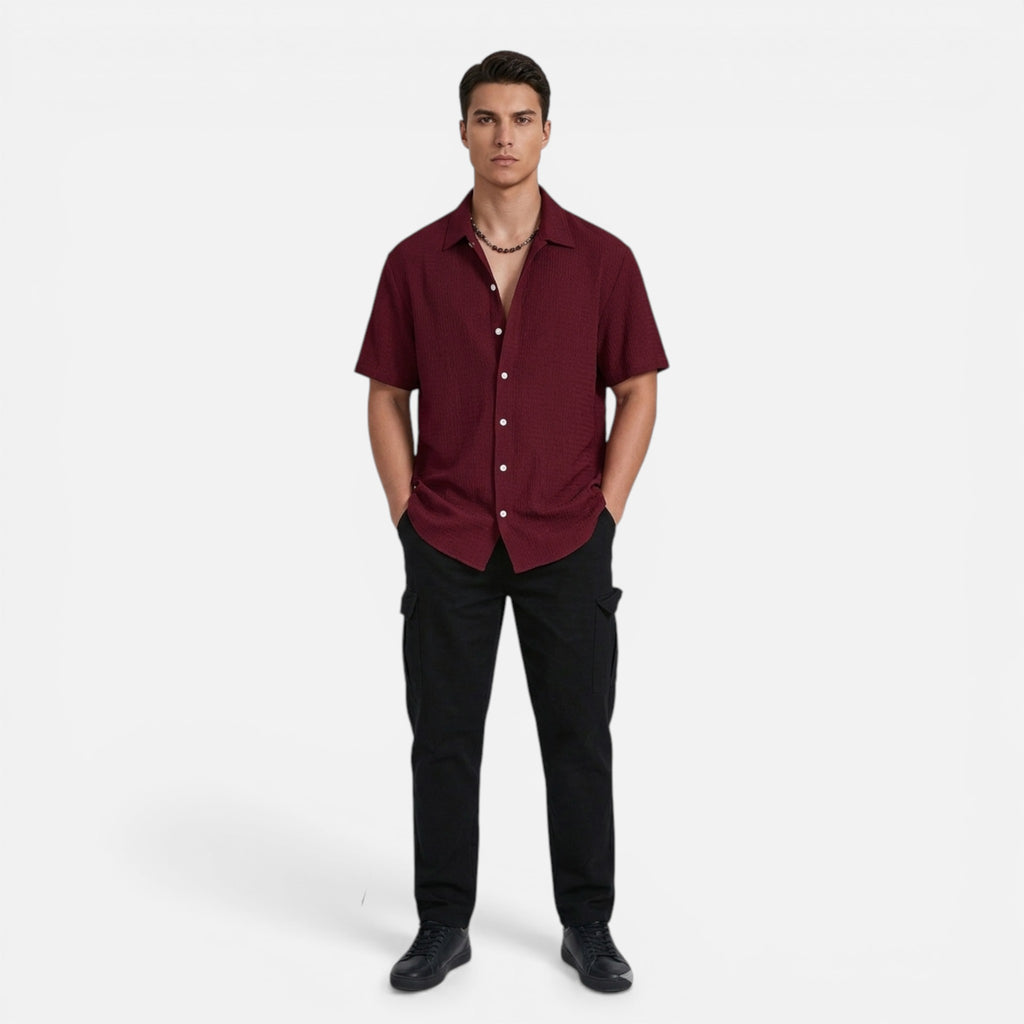 Man wearing a maroon shirt and black pants on a white background