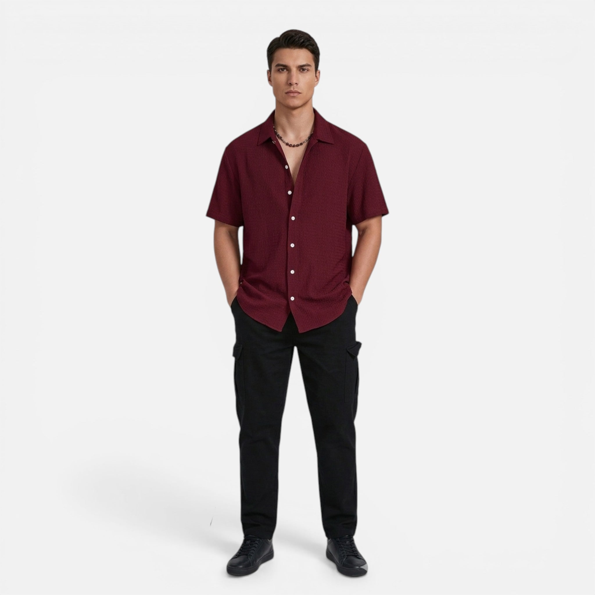 Man wearing a maroon shirt and black pants on a white background