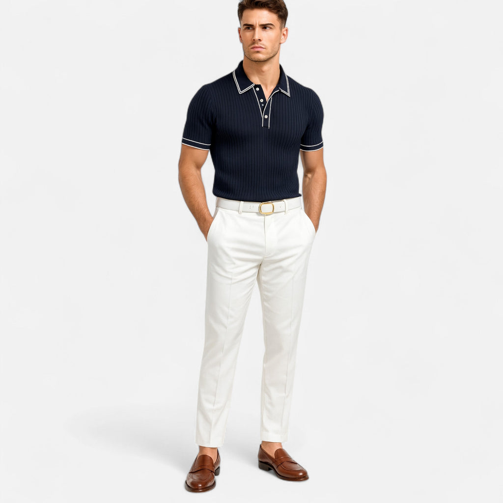 Man wearing a navy polo shirt and white pants on a light gray background