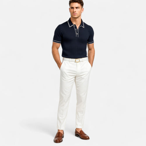 Man wearing a navy polo shirt and white pants on a light gray background