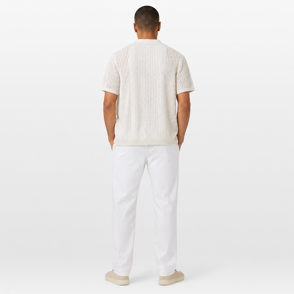 Man wearing a white ribbed sweater and white pants on a white background