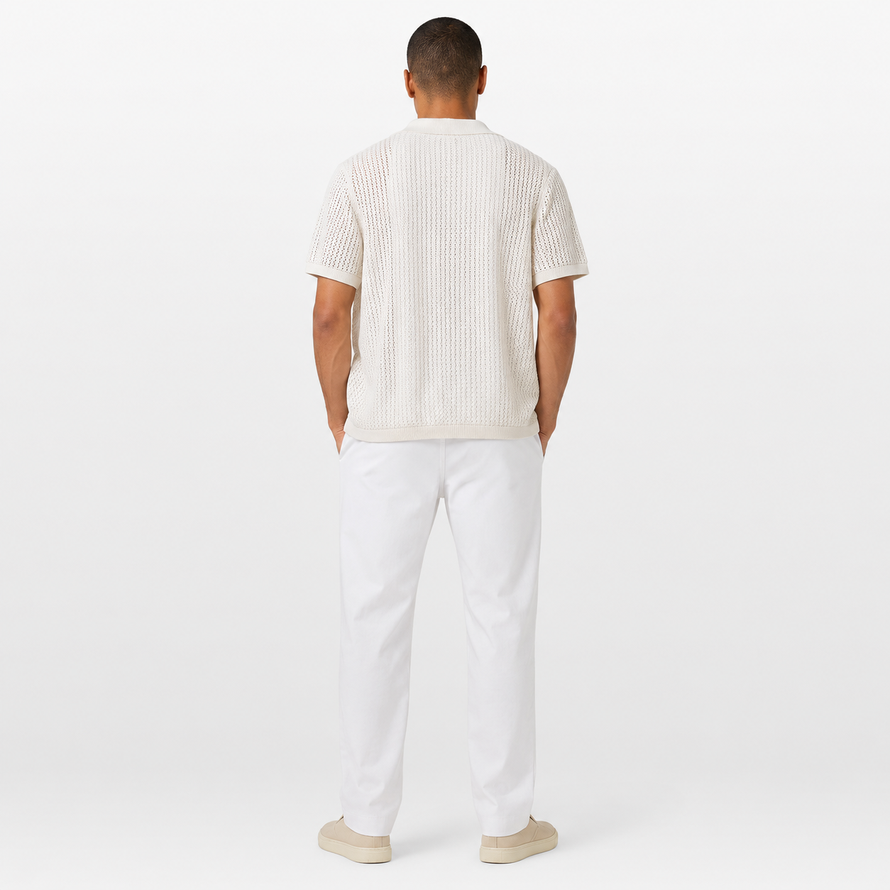 Man wearing a white ribbed sweater and white pants on a white background