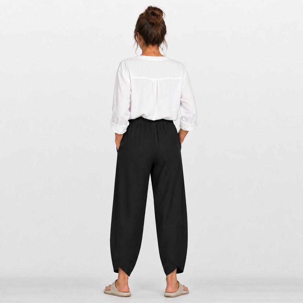 Person wearing a white shirt and black pants on a plain background