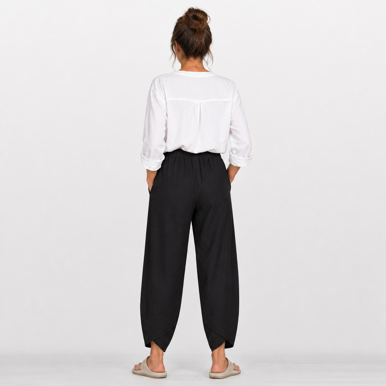 Person wearing a white shirt and black pants on a plain background
