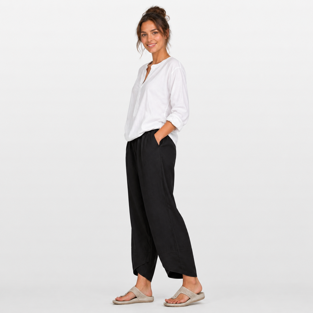 Woman wearing a white shirt and black pants on a light gray background