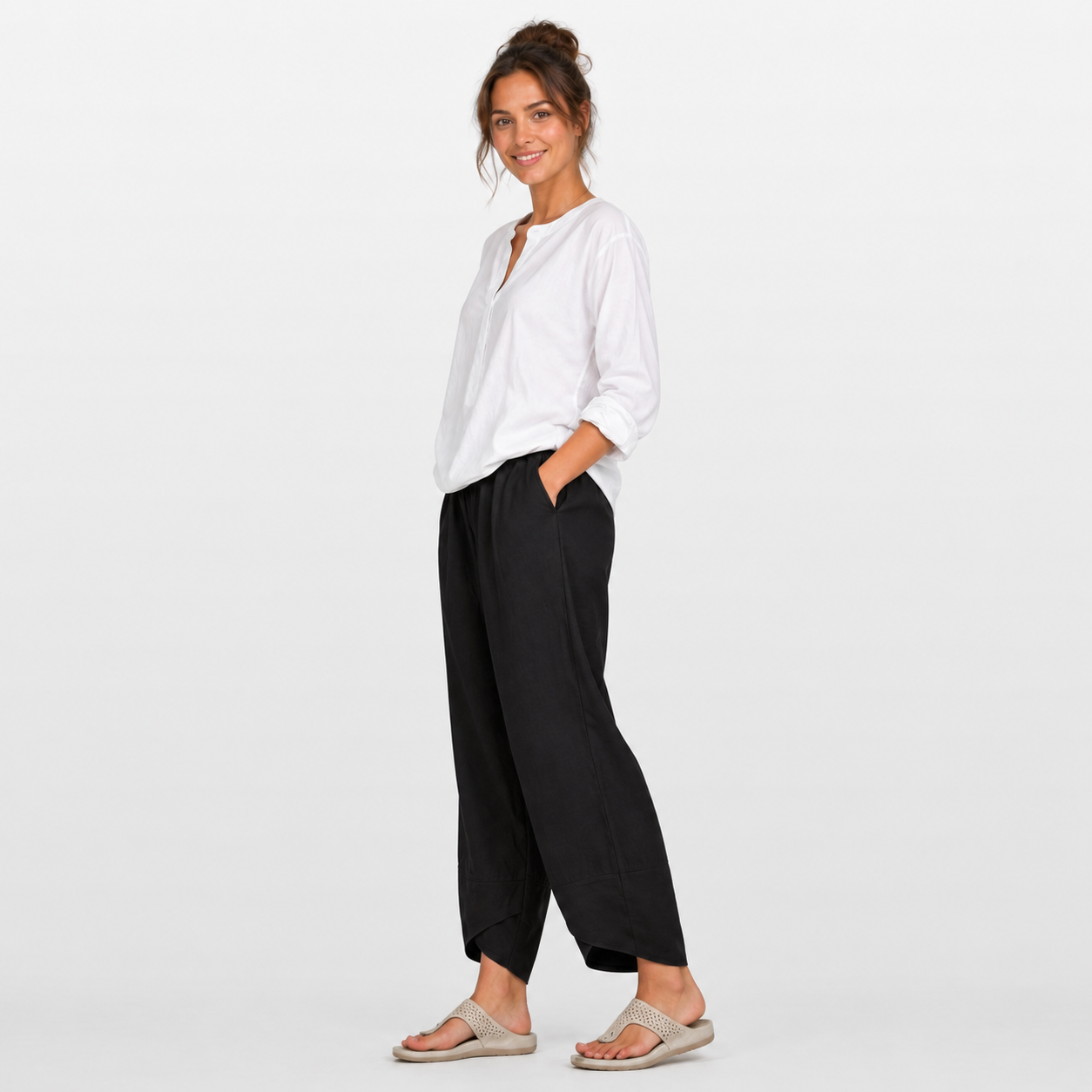 Woman wearing a white shirt and black pants on a light gray background