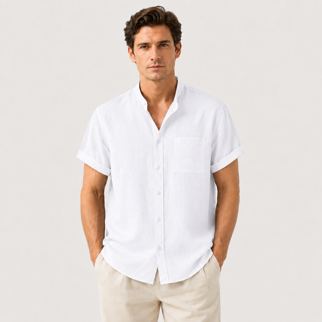Man wearing a white short-sleeve shirt and beige pants against a light gray background