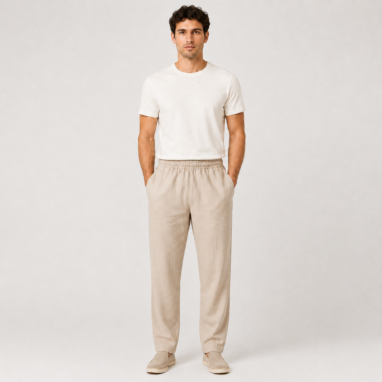 Man wearing a white t-shirt and beige pants on a plain background