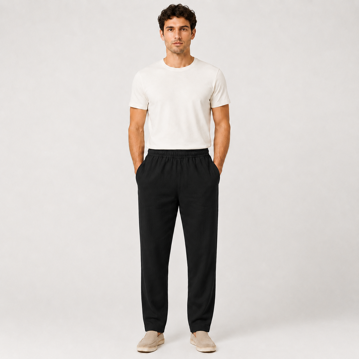 Man wearing a white t-shirt and black pants on a plain background