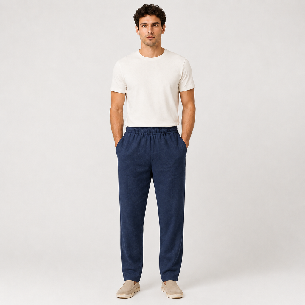 Man wearing a white t-shirt and navy pants on a plain background