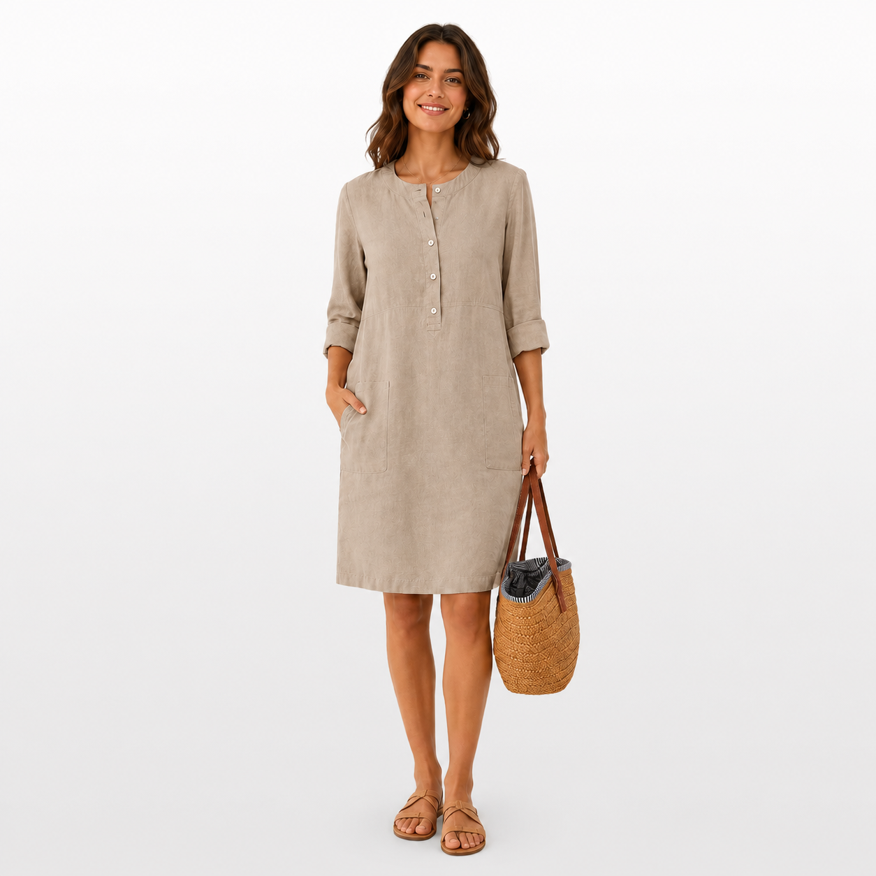 Woman wearing a beige dress holding a woven bag on a white background