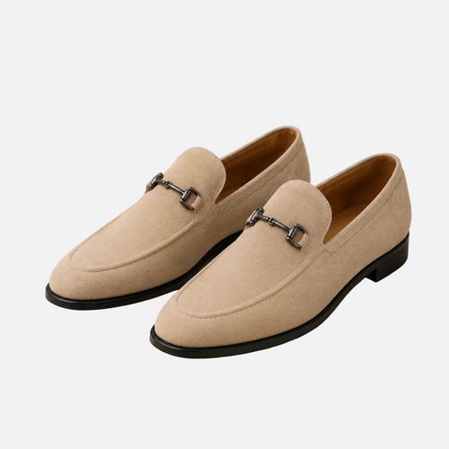 Pair of beige loafers with black soles on a beige background
