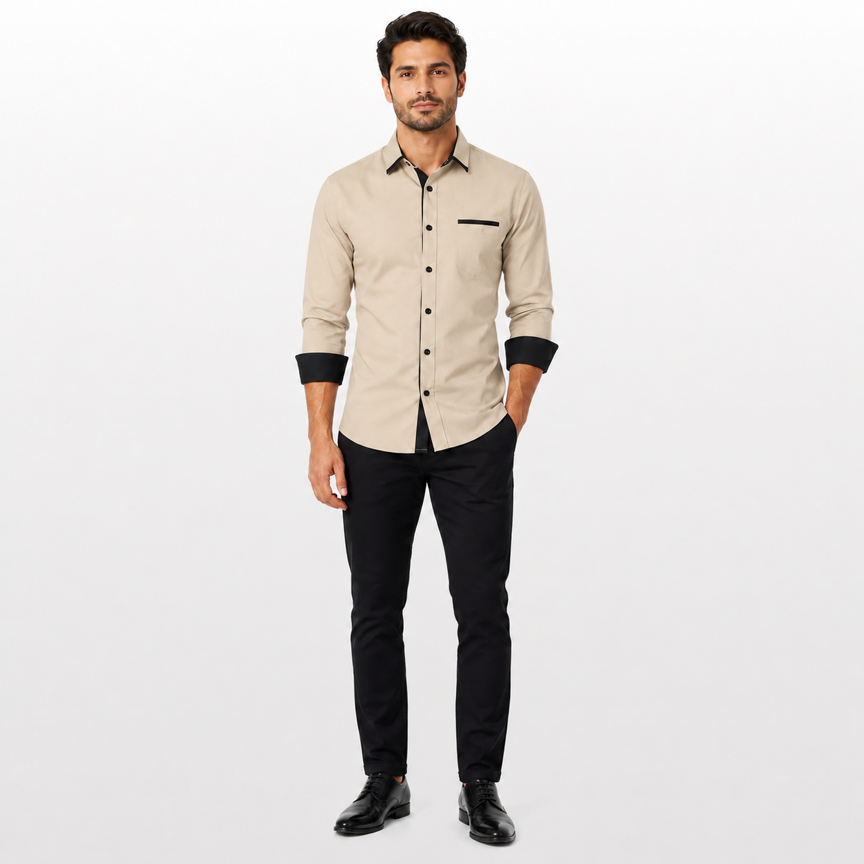 Man wearing a beige shirt with black cuffs and trim, paired with black pants on a white background