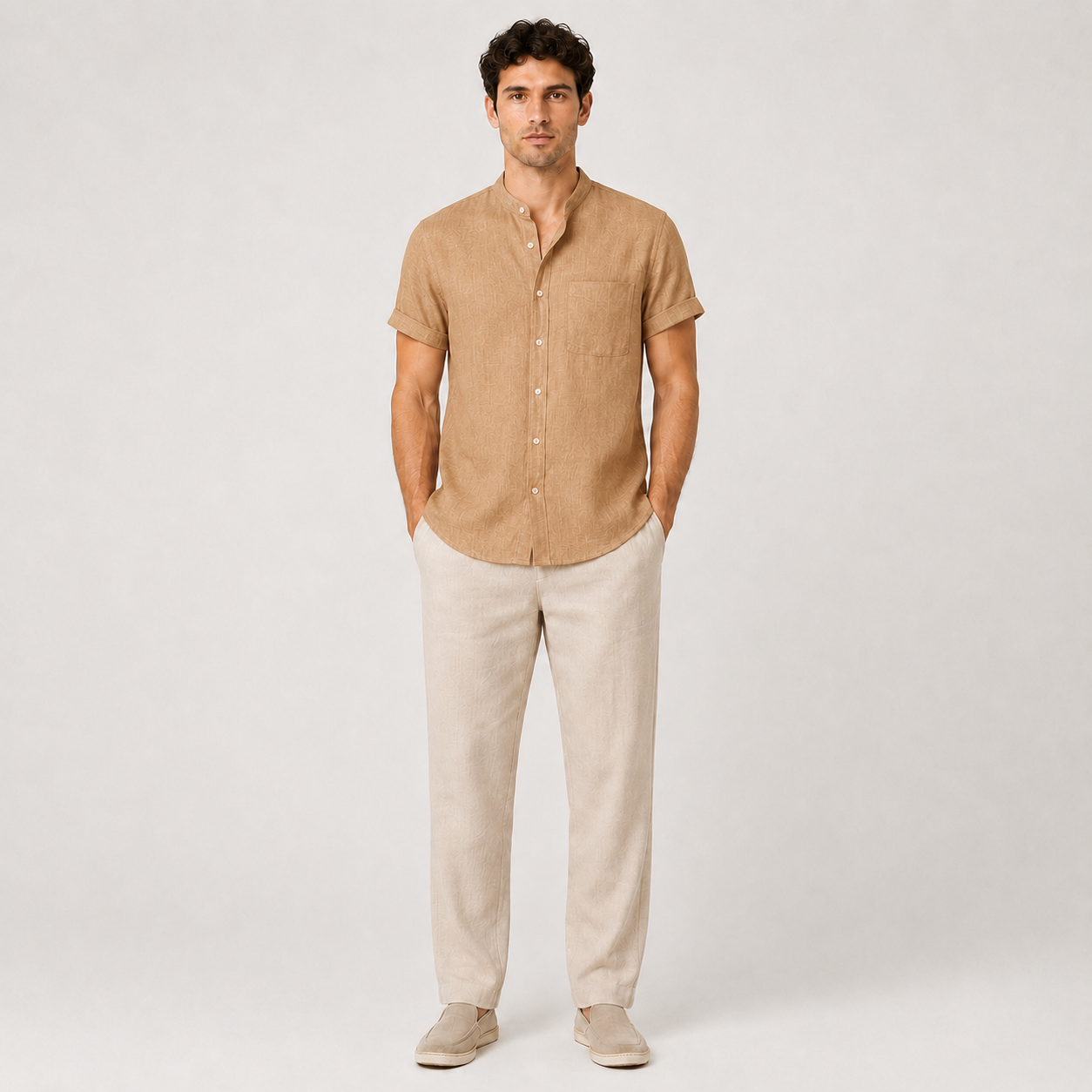Man wearing a beige short-sleeve shirt and light-colored pants on a white background