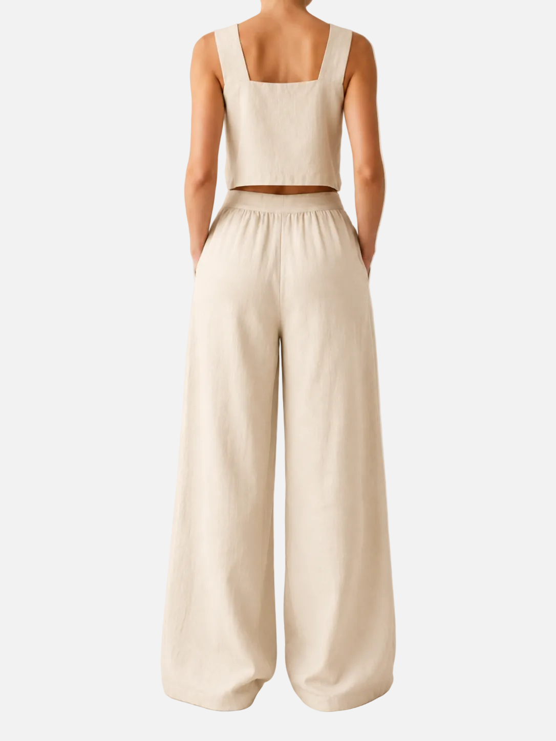 Person wearing a beige sleeveless top and wide-leg pants on a plain background