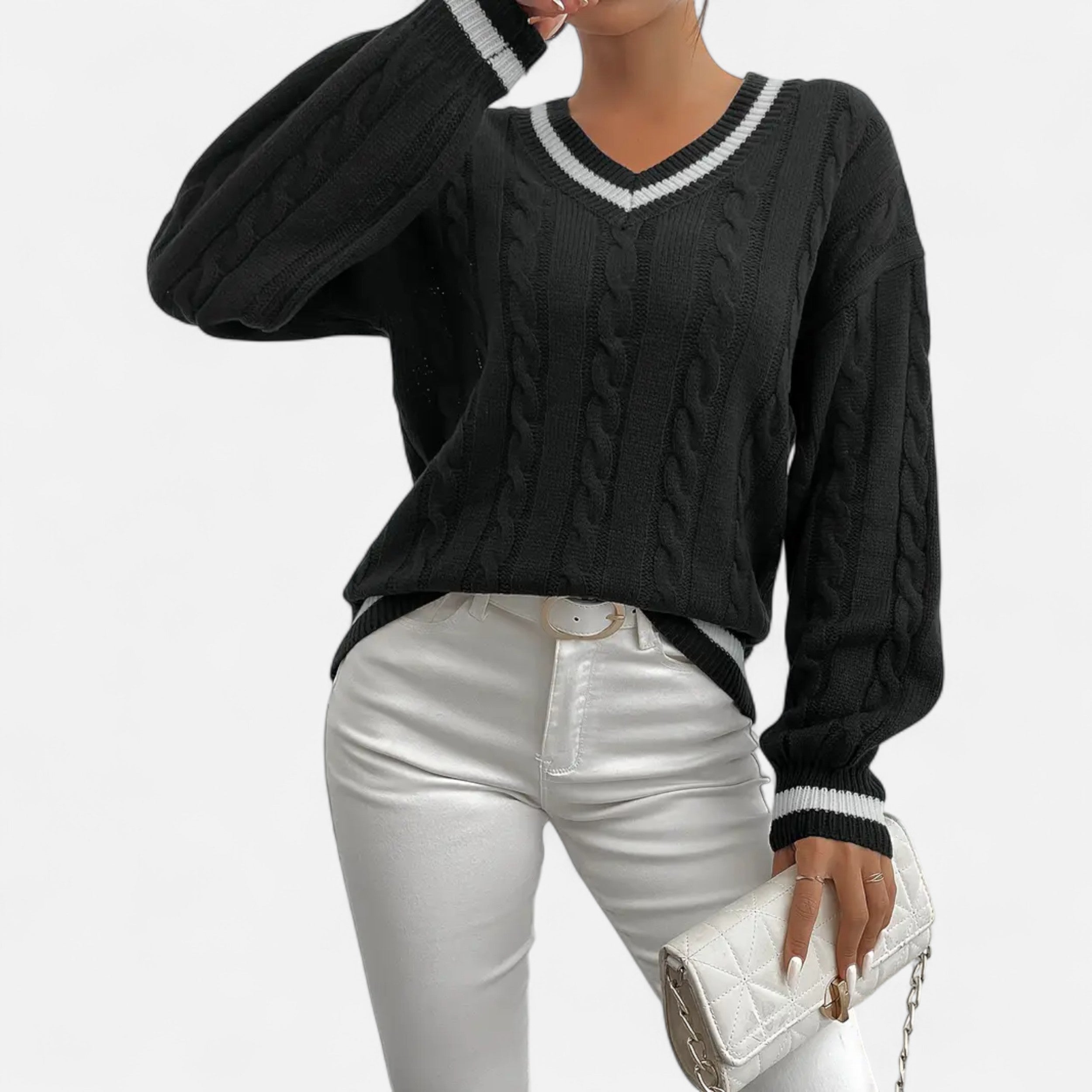 Person wearing a black cable knit sweater and silver pants on a white background