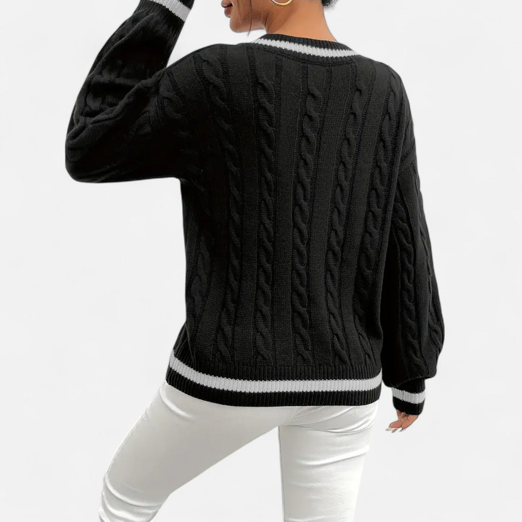 Person wearing a black cable knit sweater with white trim on a white background