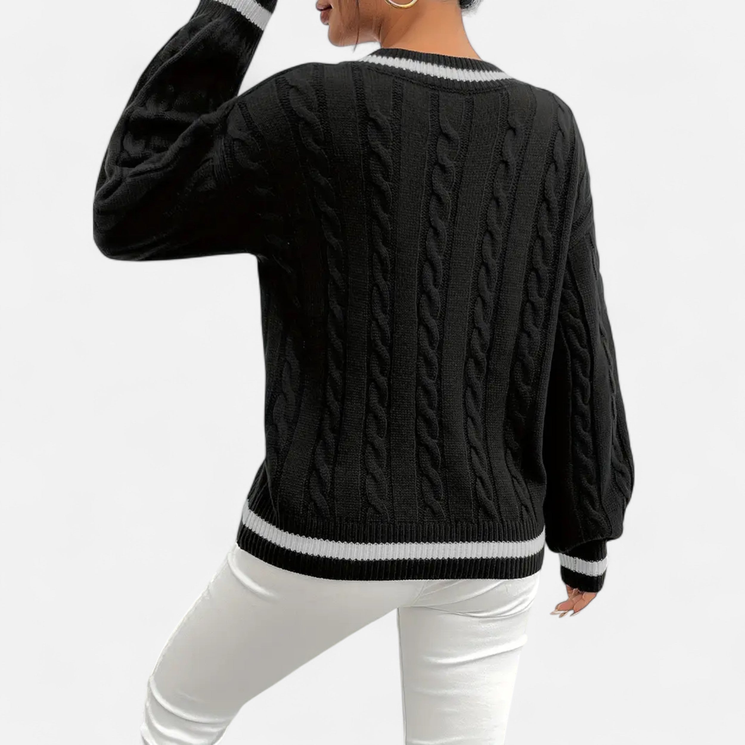 Person wearing a black cable knit sweater with white trim on a white background
