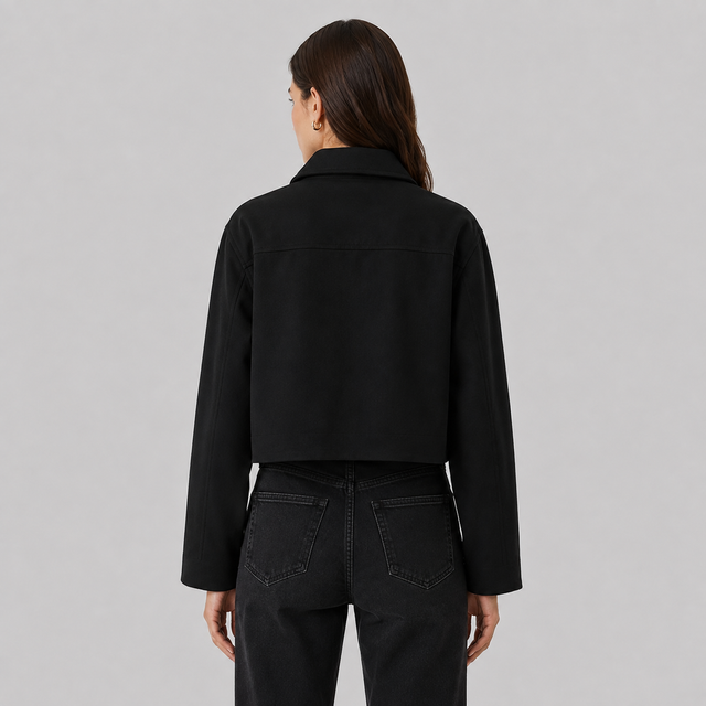 A model shown from the back wearing a black cropped long-sleeve jacket and black jeans against a solid light gray background.