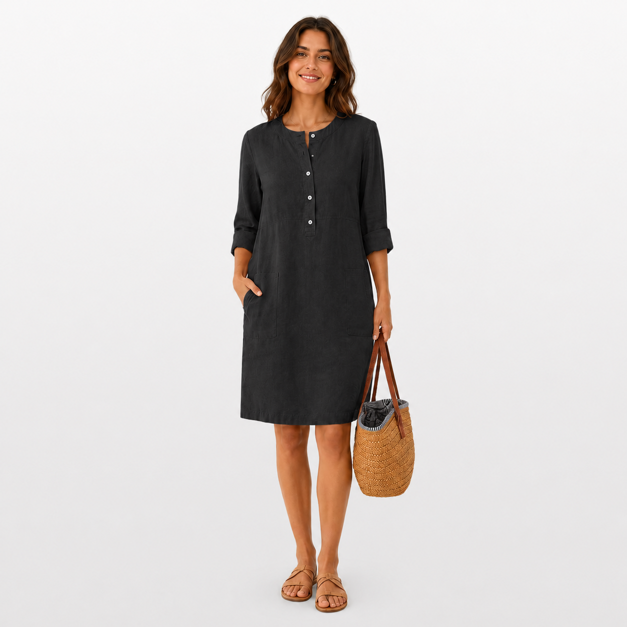 Woman wearing a black dress holding a woven bag on a white background