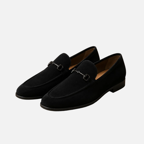 Pair of black loafers on a beige background