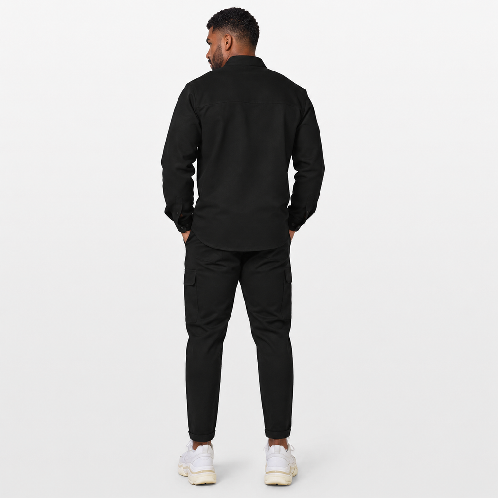 Man wearing a black outfit with white sneakers on a white background