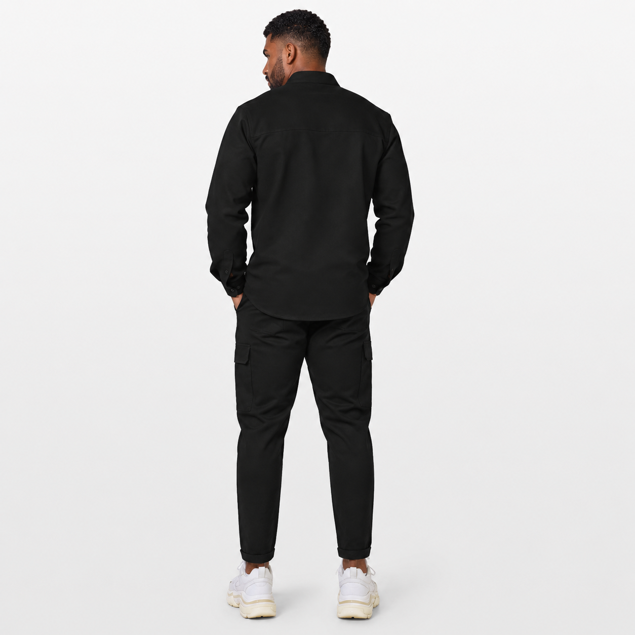 Man wearing a black outfit with white sneakers on a white background
