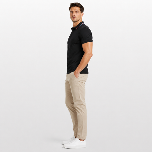Man wearing a black polo shirt and beige pants on a white background