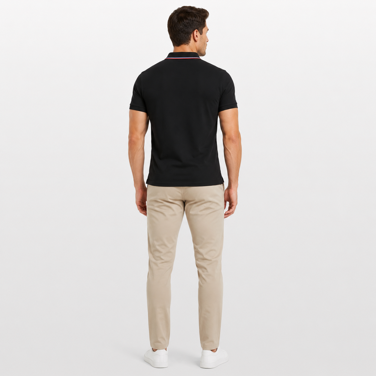 Man wearing a black polo shirt and beige pants on a white background