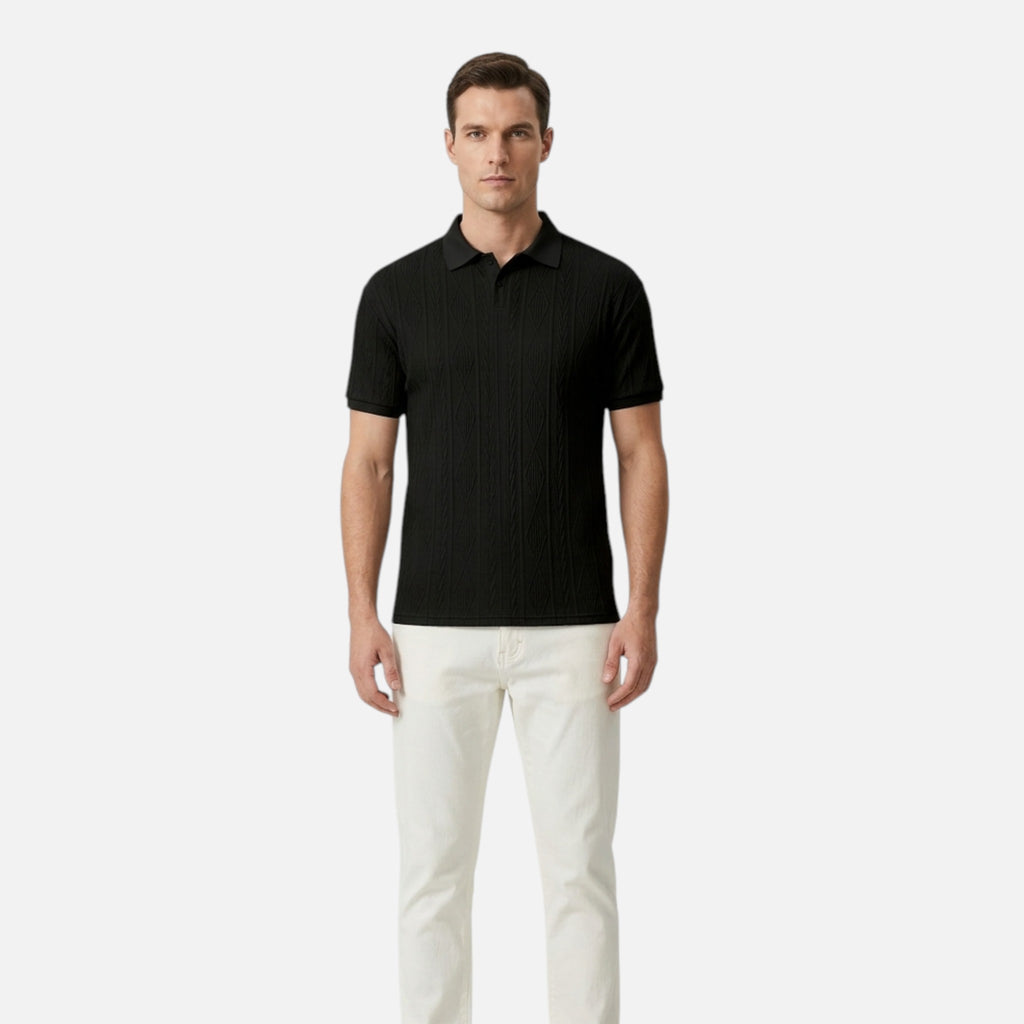 Man wearing a black polo shirt and white pants on a light gray background