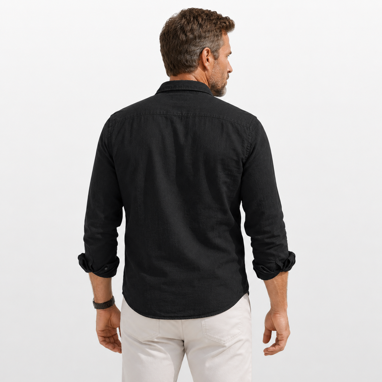 Man wearing a black shirt and white pants on a light gray background