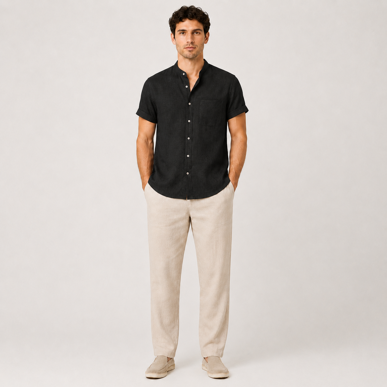 Man wearing a black short-sleeve shirt and beige pants on a white background