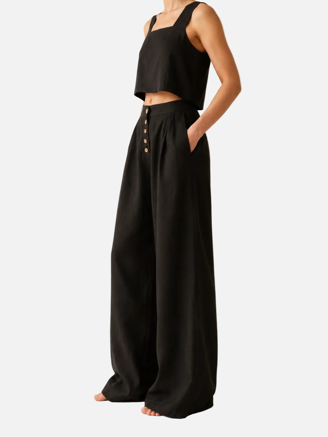 Person wearing a black sleeveless top and wide-leg pants on a beige background