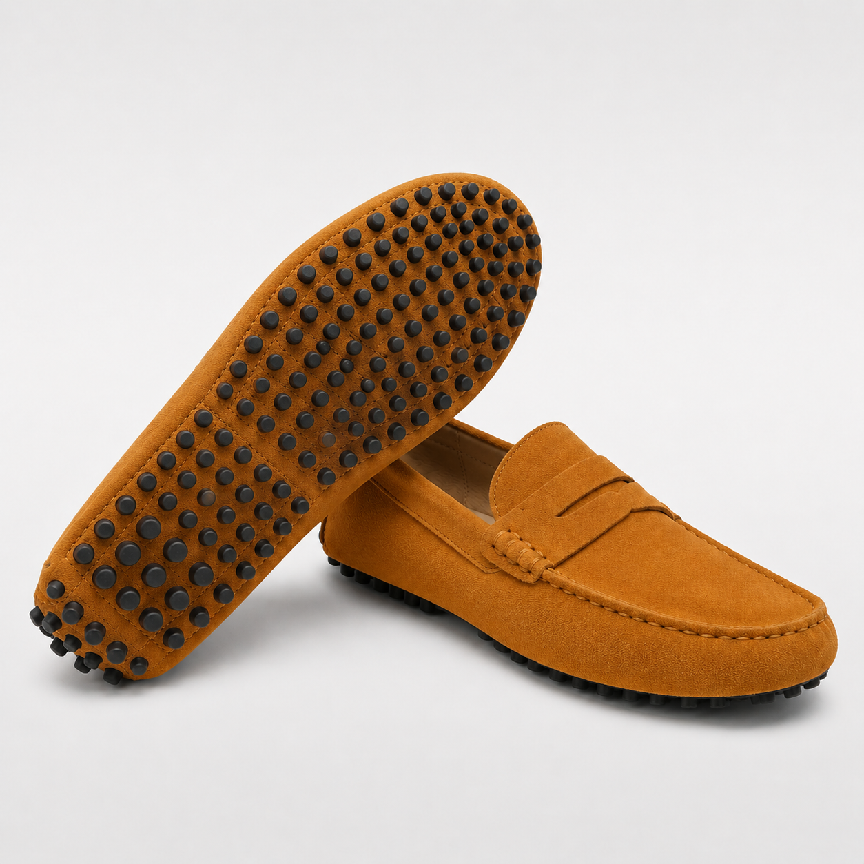Pair of brown loafers with black tread pattern on a light gray background
