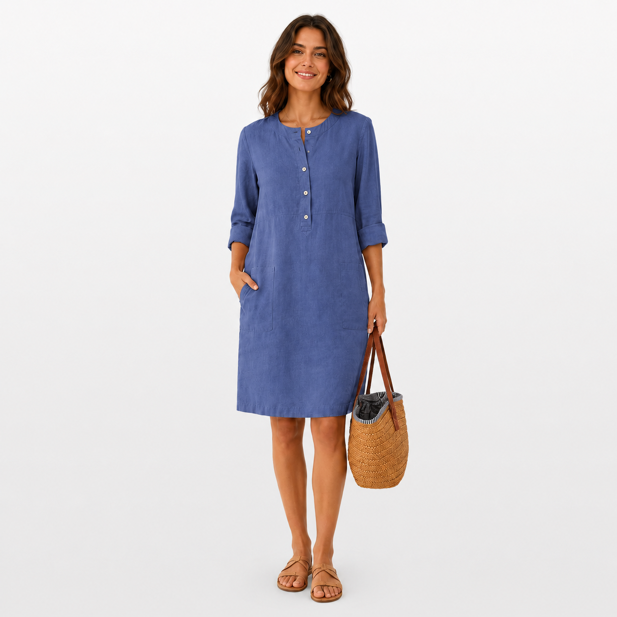 Woman wearing a blue dress holding a woven bag on a white background