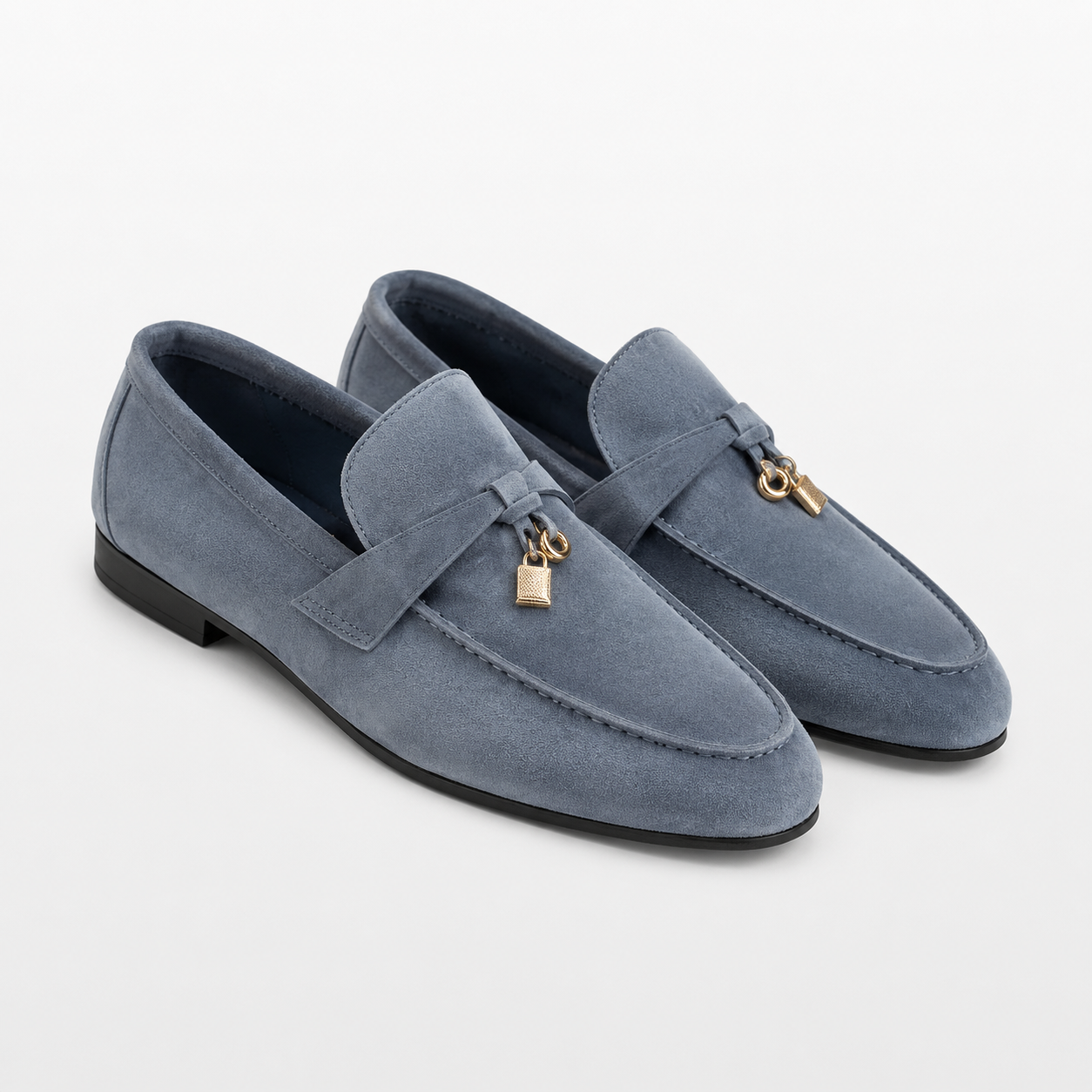 Pair of blue loafers with gold accents on a white background