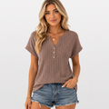 Woman wearing a brown ribbed henley shirt and denim shorts on a white background